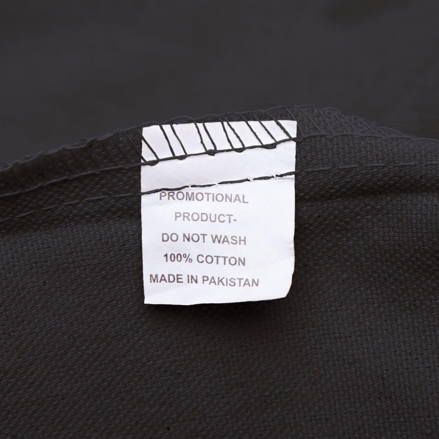 Label on black fabric indicating 'Promotional Product, Do Not Wash, 100% Cotton, Made in Pakistan'.