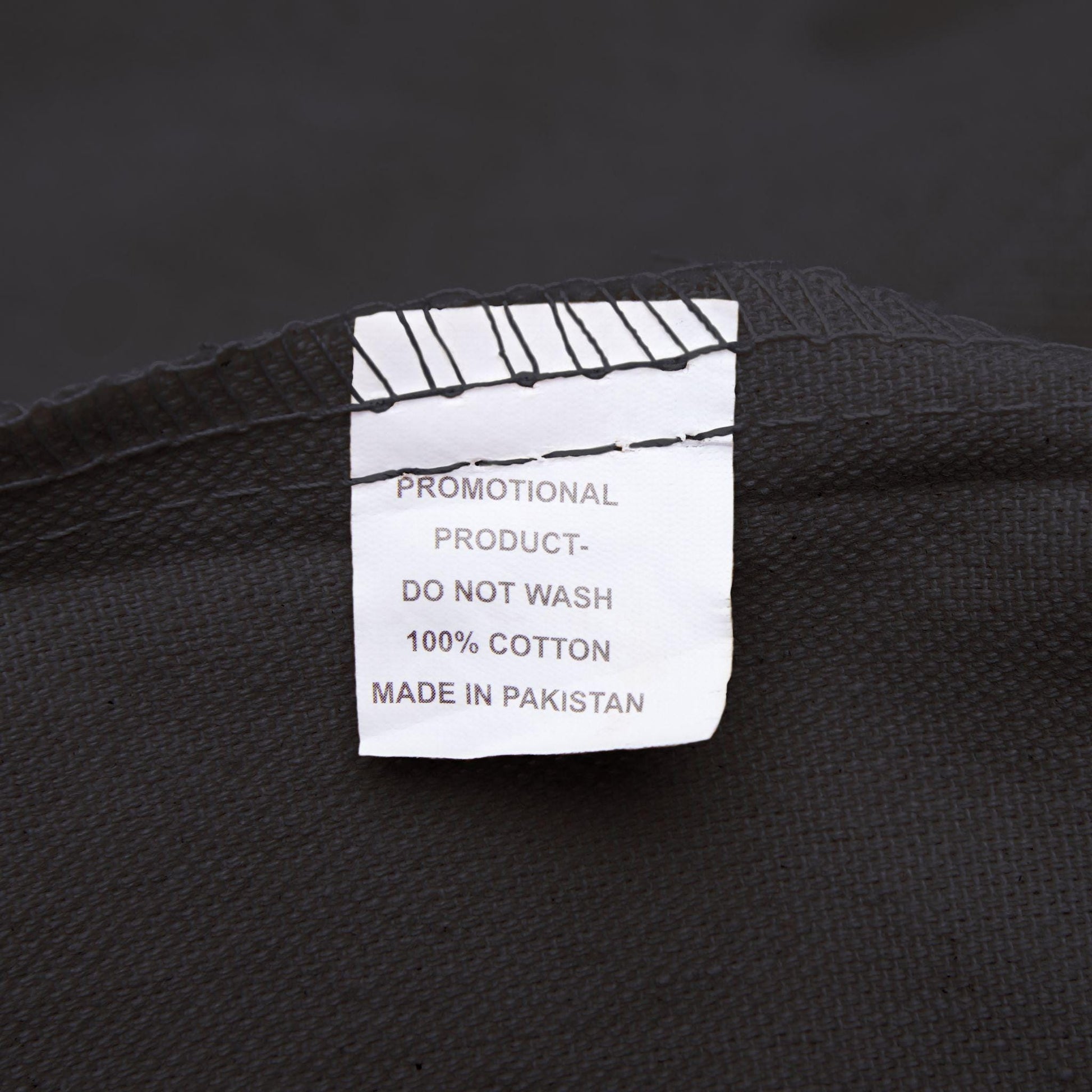 Label on black fabric indicating 'Promotional Product, Do Not Wash, 100% Cotton, Made in Pakistan'.
